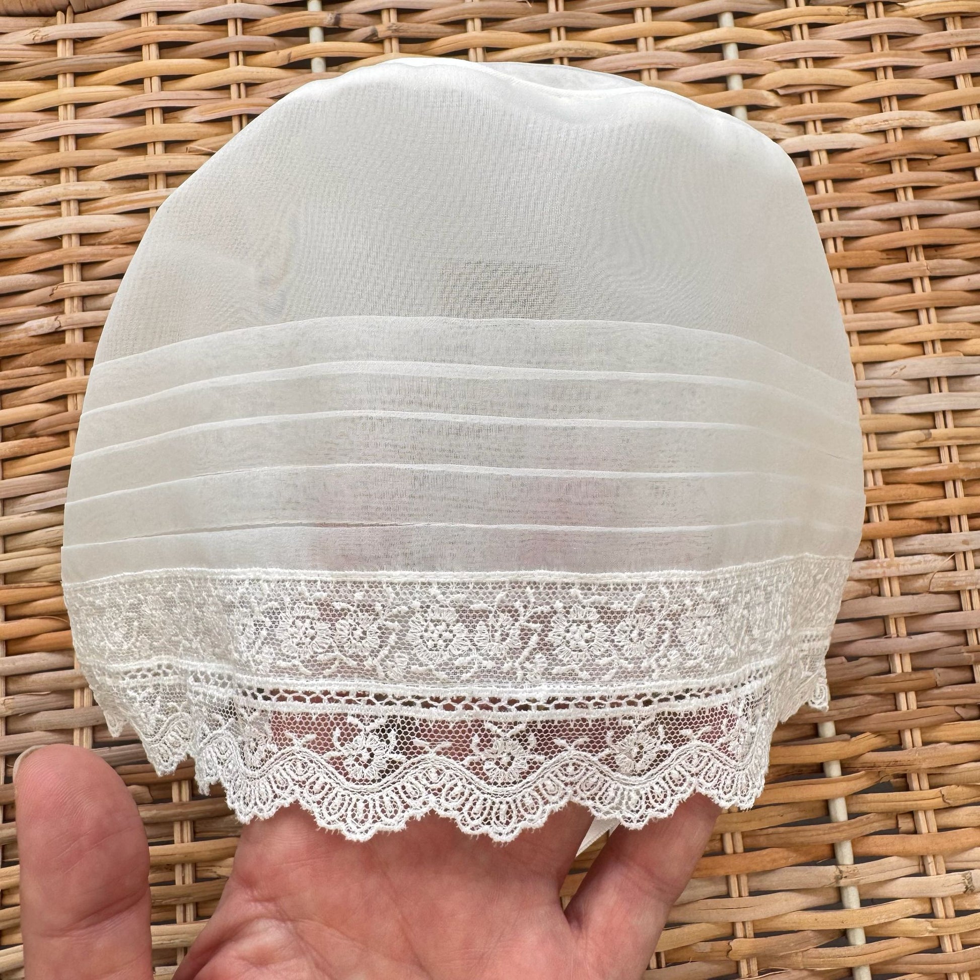 Cuffietta battesimo bimba bianca con pizzo floreale ricamato e laccetti in raso.