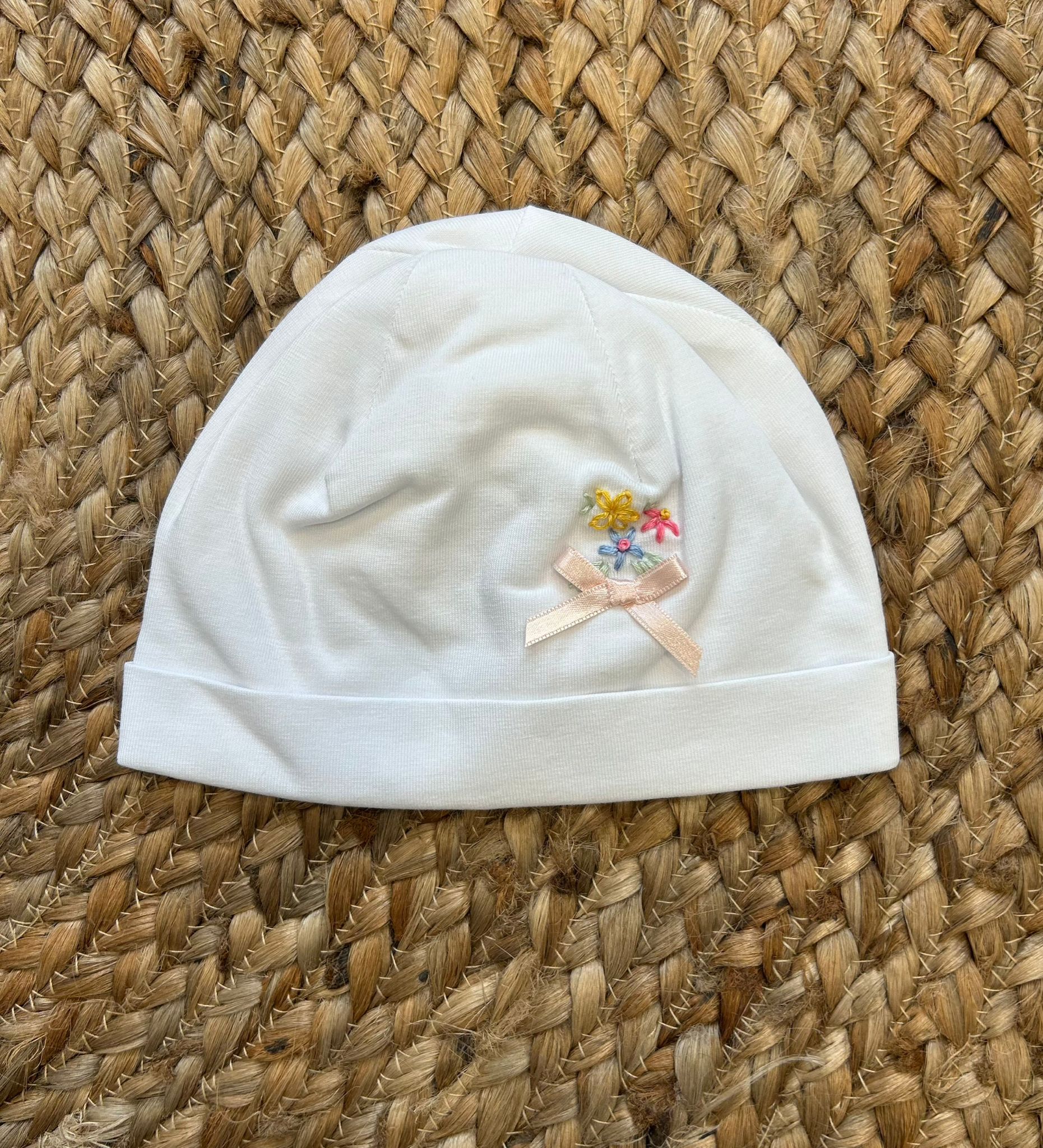 Cappellino neonato bianco con fiocchetto rosa e ricami floreali