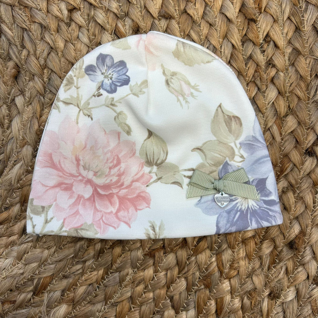 Cappellino floreale da neonata con fiocco salvia e ciondolo a cuore, in jersey panna.