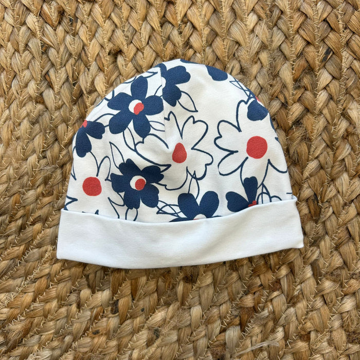 Cappellino neonata bianco con stampa floreale navy e dettagli corallo.
