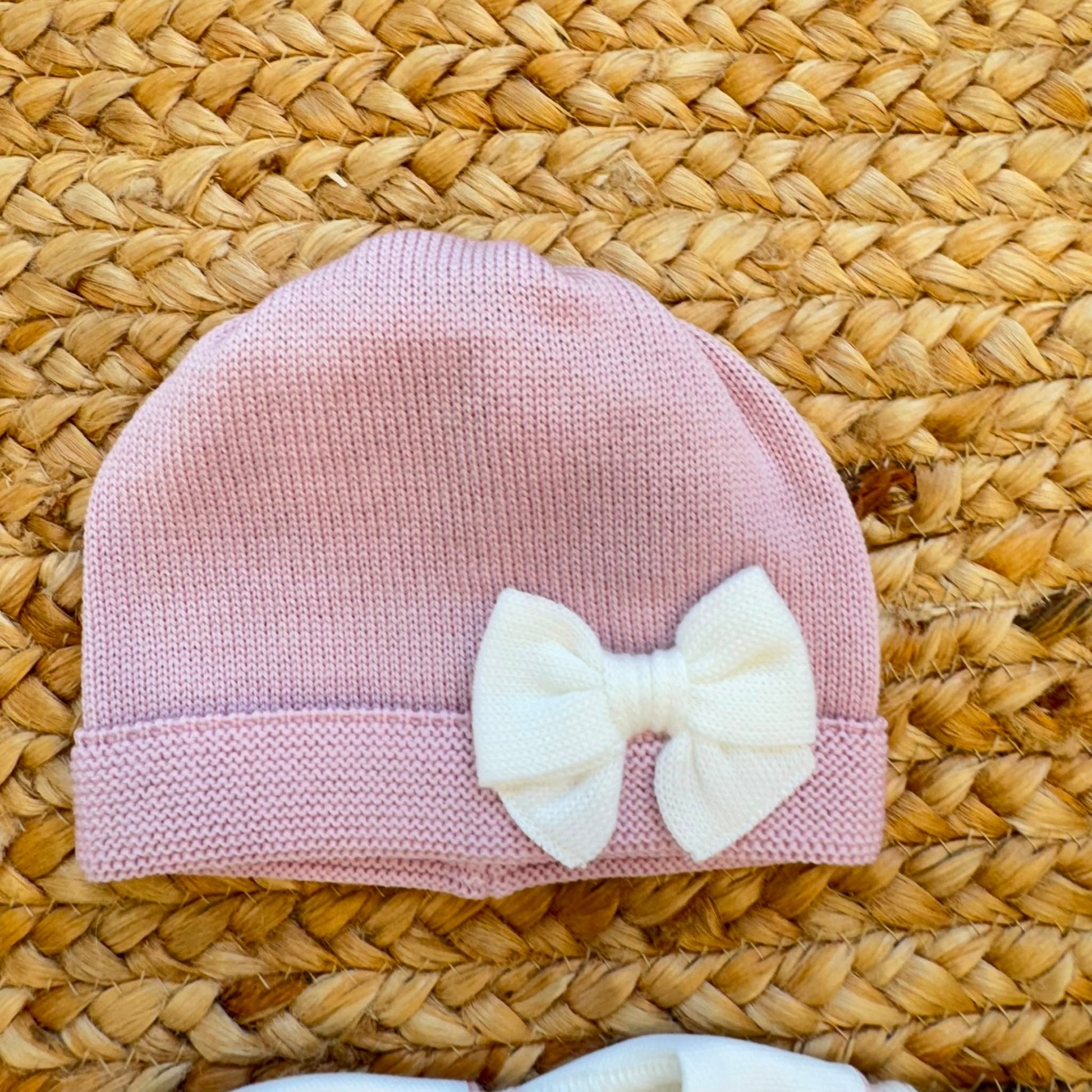 Uscita clinica neonata in pura lana bianca con fiocco rosa e copertina coordinata.