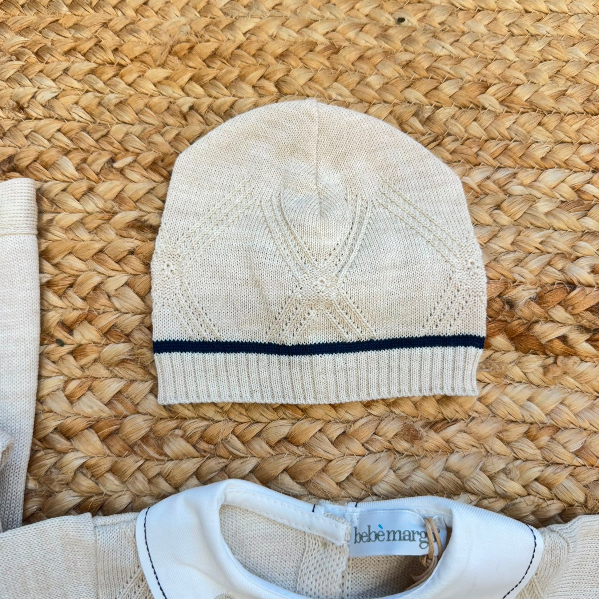 Dettaglio corredino nascita neonato con tessile bianco e orsetto ricamato beige