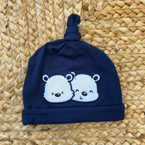 Cappellino neonato blu con due orsetti ricamati e nodo in cima.