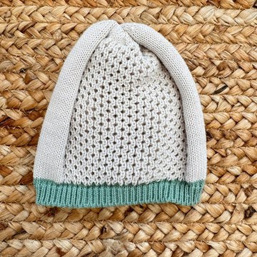 cappellino in maglia beige per neonato con bordo verde salvia, lavorazione a nido d’ape
