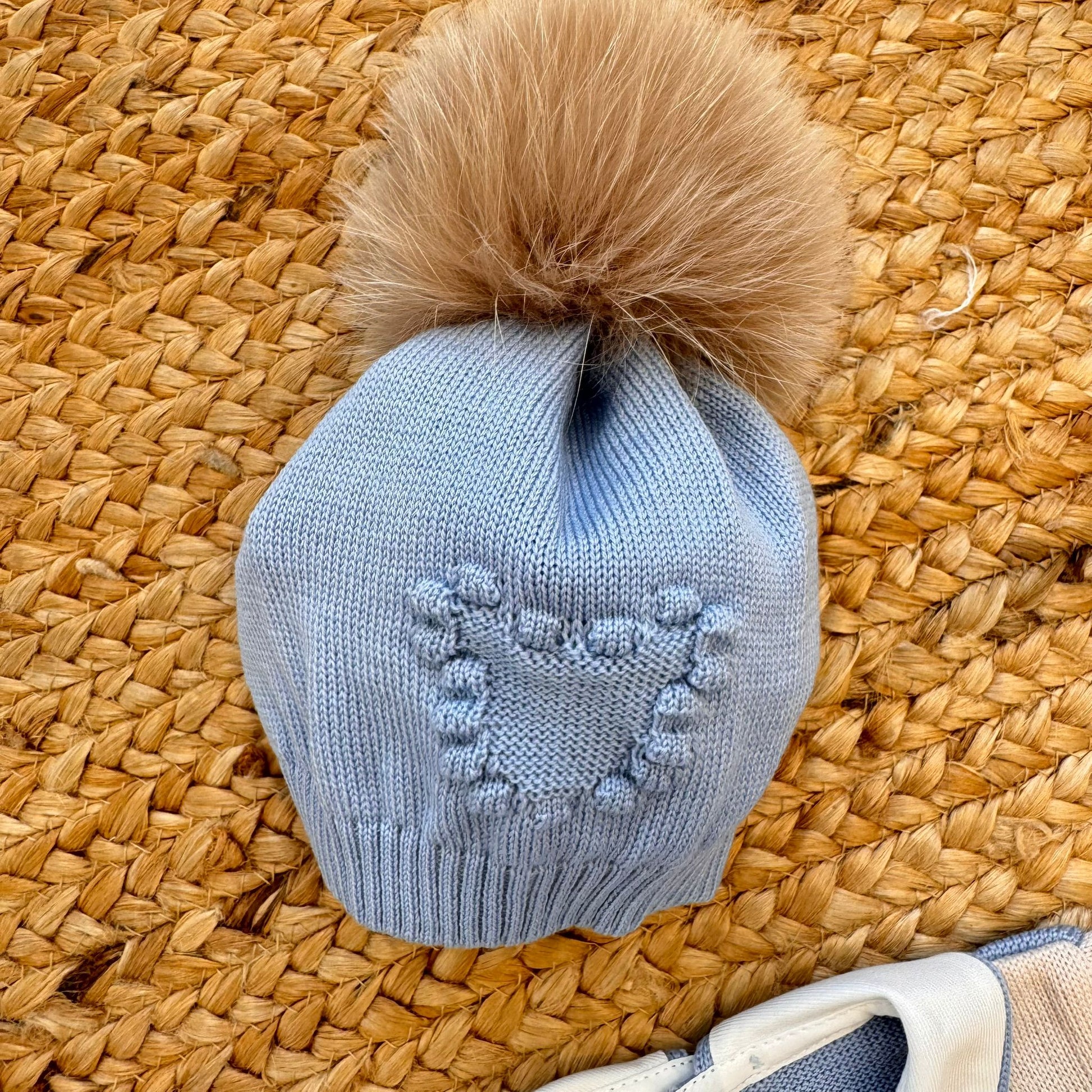 cappellino neonato in pura lana azzurra con pompon eco-pelliccia