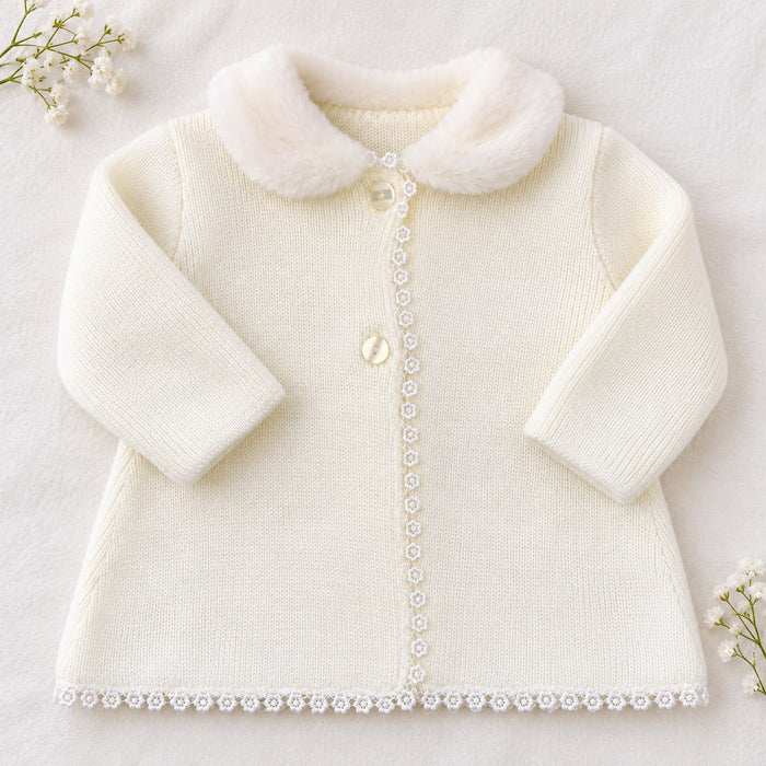 Cappottino battesimo bimba panna in maglia con colletto arrotondato effetto pelliccia, bottoni chiari e passamaneria floreale sul davanti.