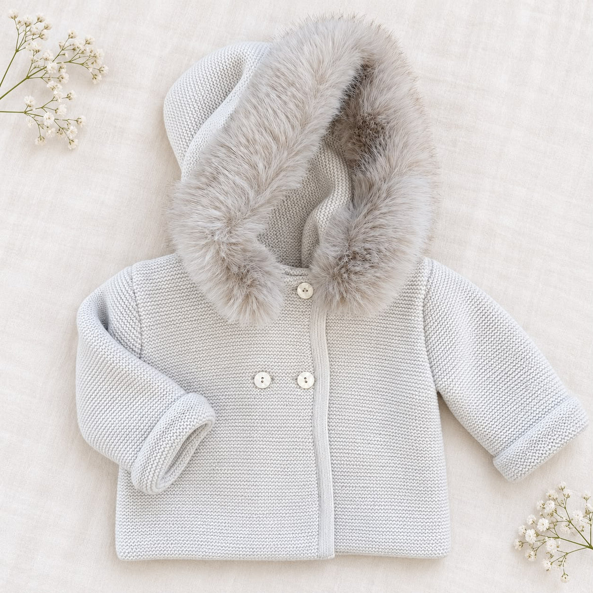 Cappottino battesimo bimbo beige chiaro in maglia con ampio cappuccio bordato effetto pelliccia, bottoni chiari e maniche lunghe.