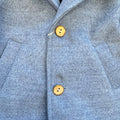 Dettaglio cappotto bimbo elegante azzurro mélange con bottoni effetto legno.