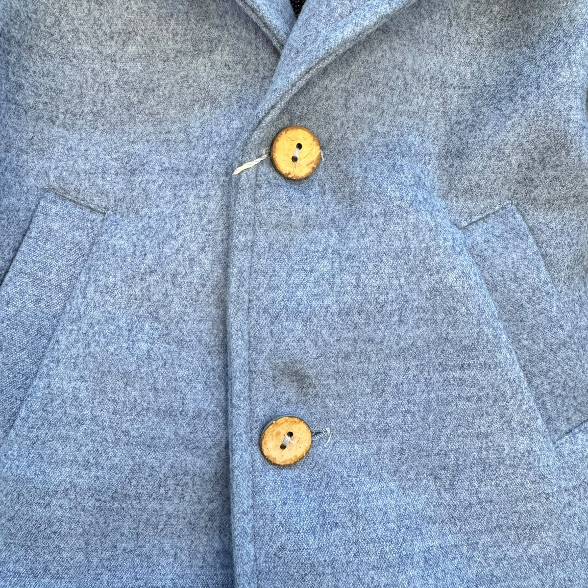 Dettaglio cappotto bimbo elegante azzurro mélange con bottoni effetto legno.