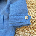 Dettaglio cappotto bimbo elegante azzurro mélange con bottoni effetto legno.