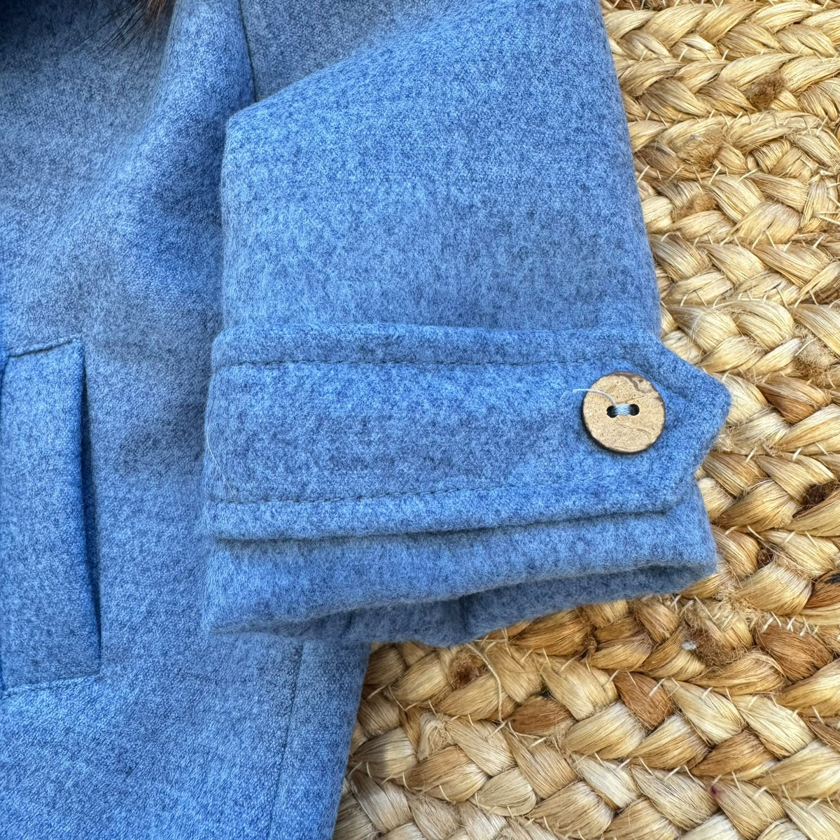 Dettaglio cappotto bimbo elegante azzurro mélange con bottoni effetto legno.