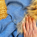 Dettaglio cappotto bimbo elegante azzurro mélange con bottoni effetto legno.