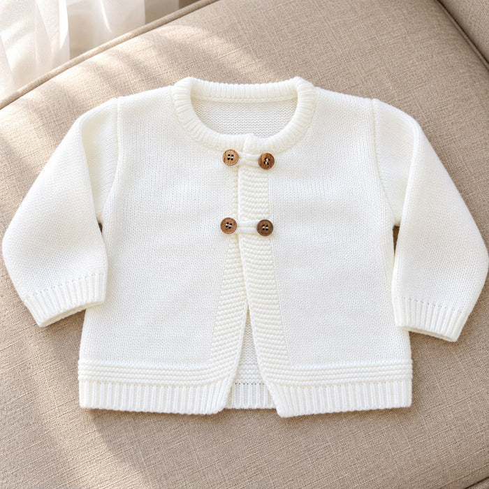 Cardigan battesimo bimbo color panna in maglia 100% acrilico, con maniche lunghe, scollo rotondo e doppi bottoni effetto legno.