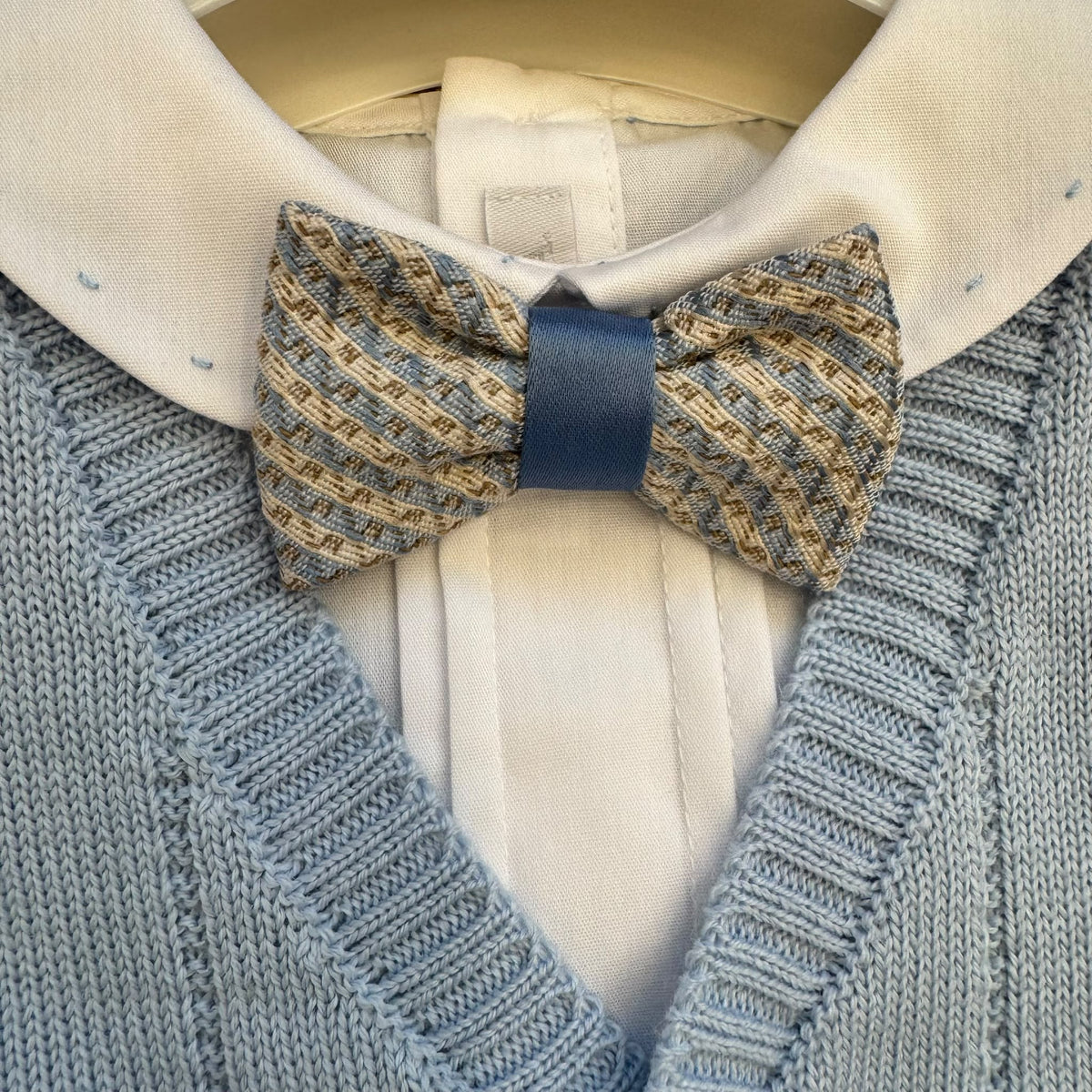 Cardigan azzurro del completo battesimo bimbo con camicia bianca e papillon fantasia.
