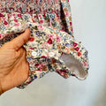 Pagliaccetto bimba floreale in cotone con punto smock e colletto a volant fucsia.