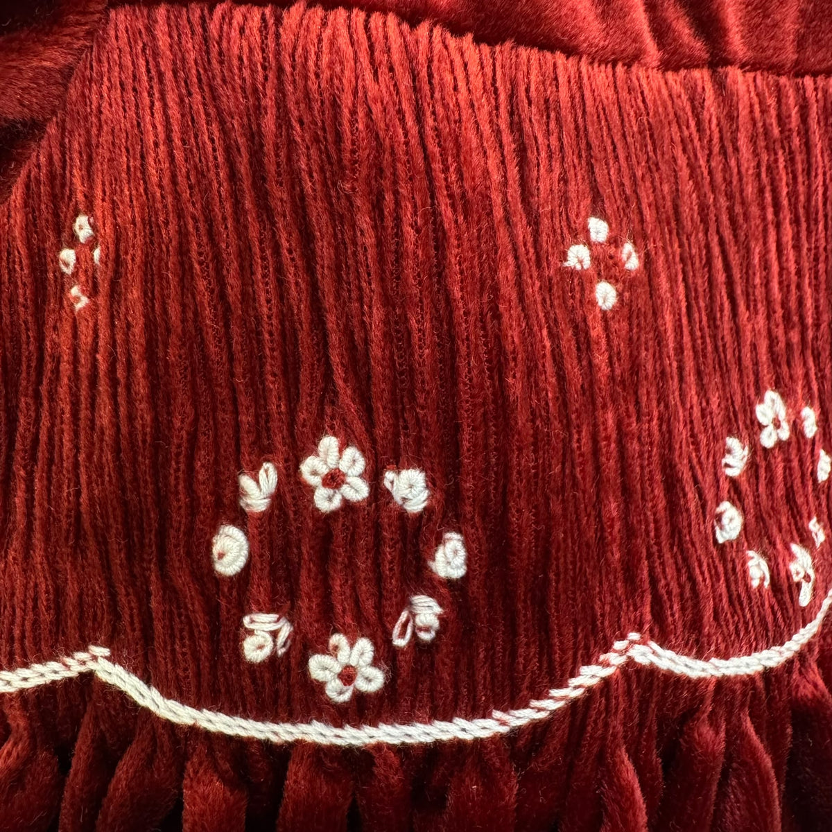 Abito bimba in velluto bordeaux con punto smock, colletto bianco a contrasto e maniche a palloncino.