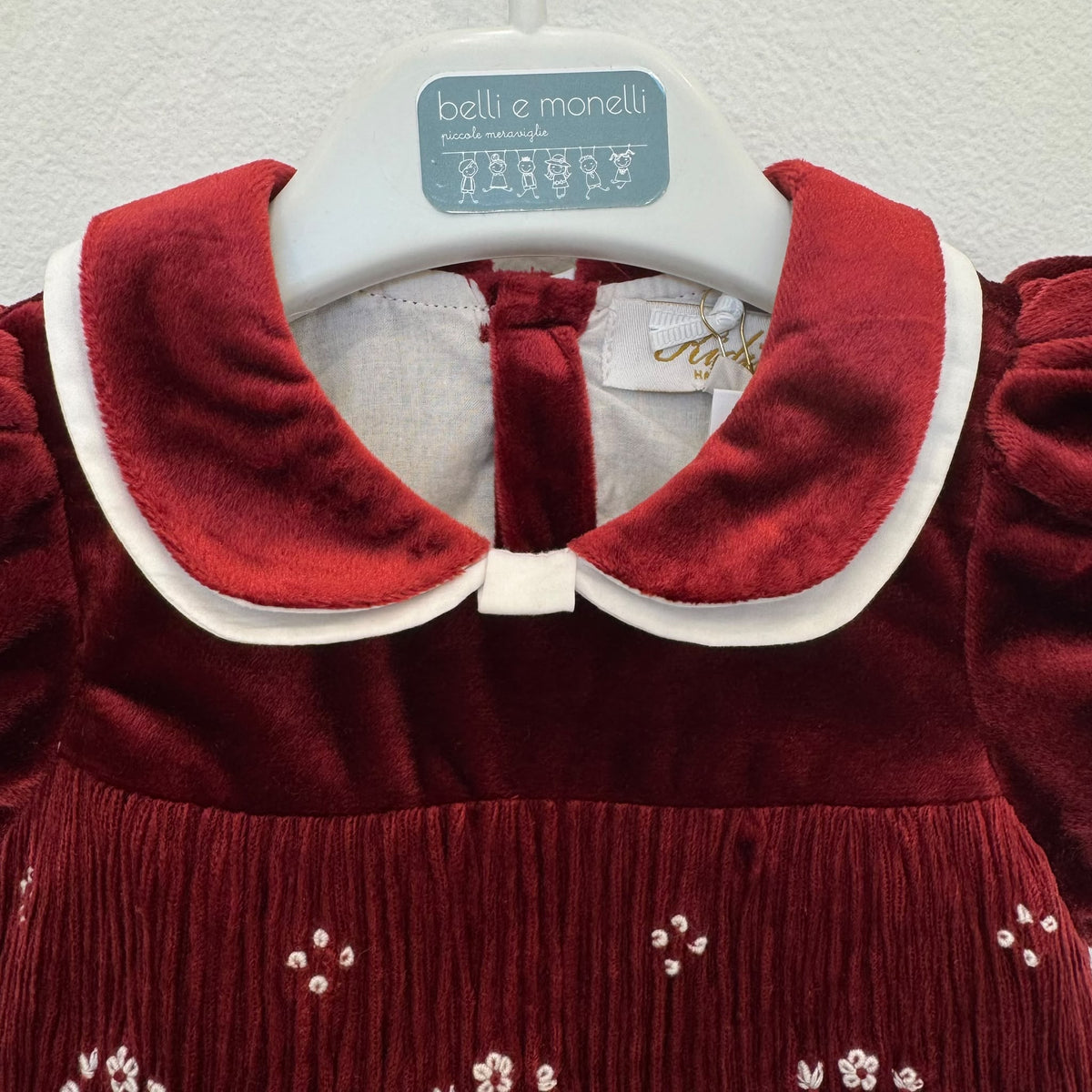 Abito bimba in velluto bordeaux con punto smock, colletto bianco a contrasto e maniche a palloncino.