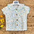 Camicia a fiori con bottoni in legno e colletto arrotondato.