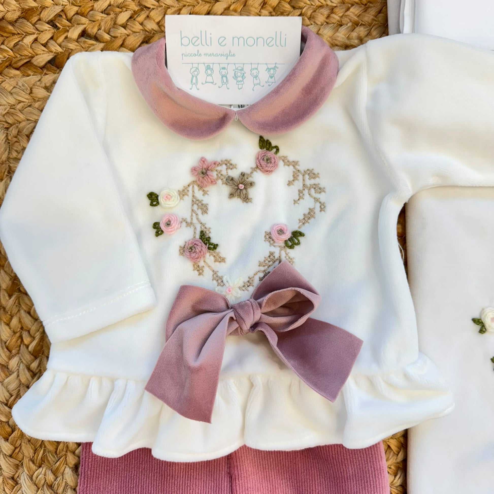 Uscita clinica neonata in ciniglia bianca e rosa con completino ricamato a cuore floreale, fiocco applicato, cappello, bavetta, scarpine, lenzuola coordinate e copertina sfoderabile.