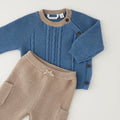 
Completo neonato in cotone e lana con maglia petrolio a trecce e pantalone beige indossato