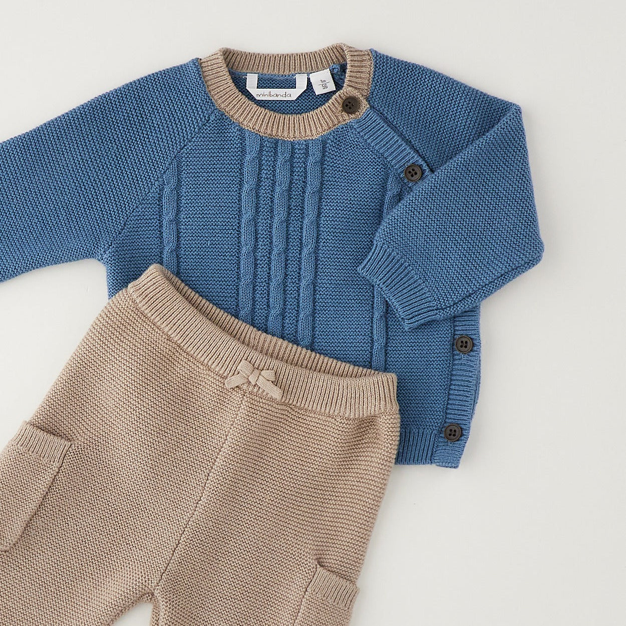 
Completo neonato in cotone e lana con maglia petrolio a trecce e pantalone beige indossato