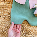Primo piano sul tessuto caldo della salopette in maglia verde salvia – abbigliamento neonata autunno inverno