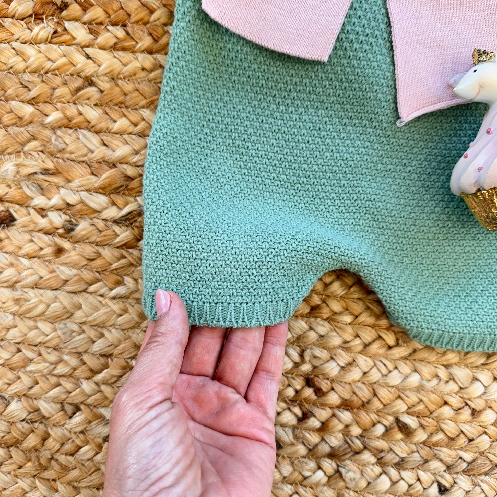 Primo piano sul tessuto caldo della salopette in maglia verde salvia – abbigliamento neonata autunno inverno