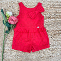 Romper rosso per bambina in cotone sangallo con fiocco decorativo e balza in vita, ideale per l'estate.