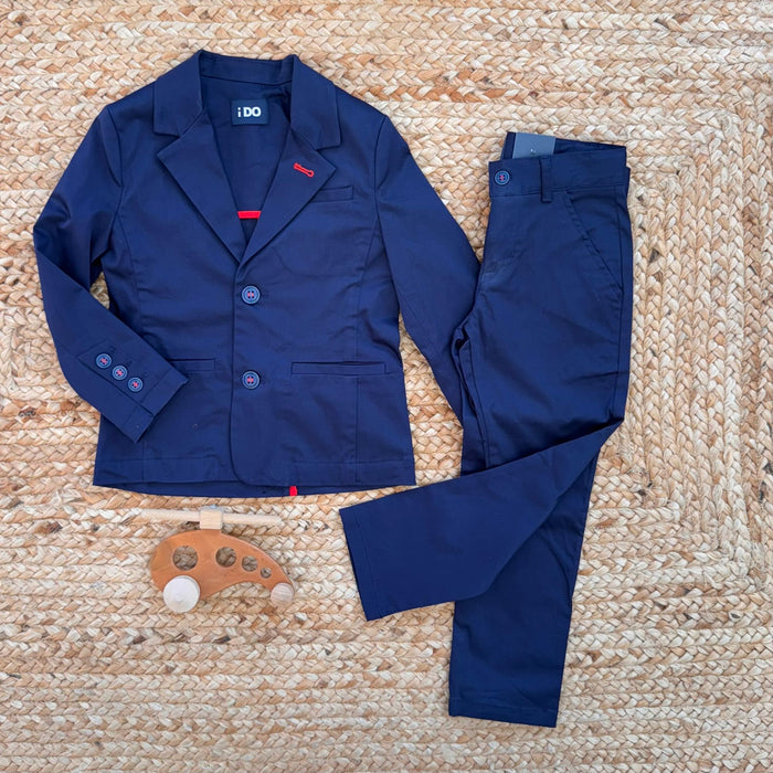 Completo bambino blu navy con giacca e pantalone, dettagli rossi e bottoni a contrasto.