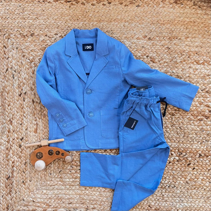 Completo bambino bluette con giacca elegante e pantalone con coulisse, su sfondo in juta.