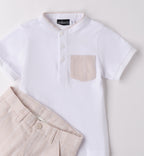 Completo bambino con t-shirt bianca con colletto e taschino e pantaloncini beige a righe verticali.