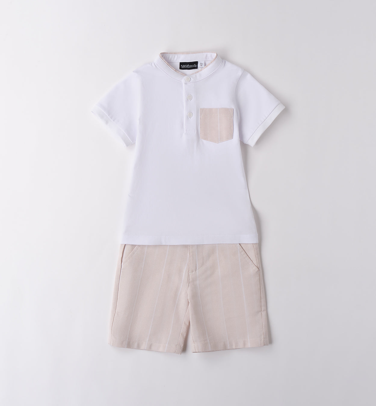 Completo bambino con t-shirt bianca con colletto e taschino e pantaloncini beige a righe verticali.

