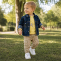 Bambino con giacca jeans blu, maglia gialla con stampa e pantalone cargo beige