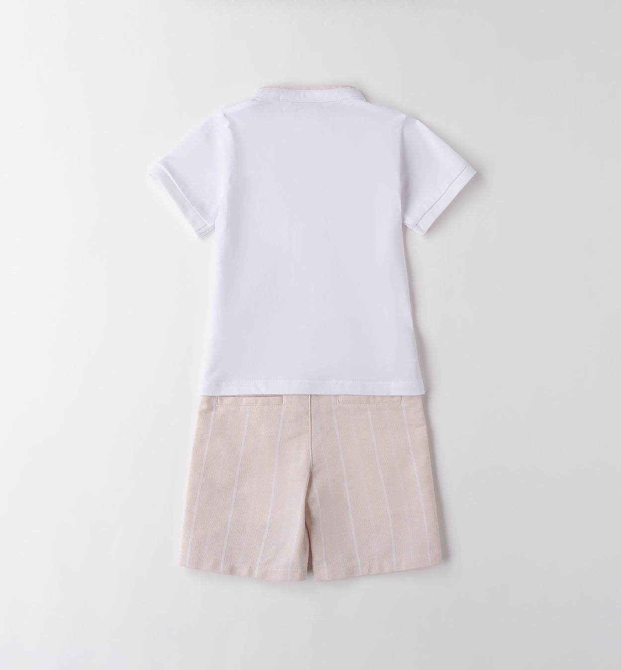 Completo bambino con t-shirt bianca con colletto e taschino e pantaloncini beige a righe verticali.