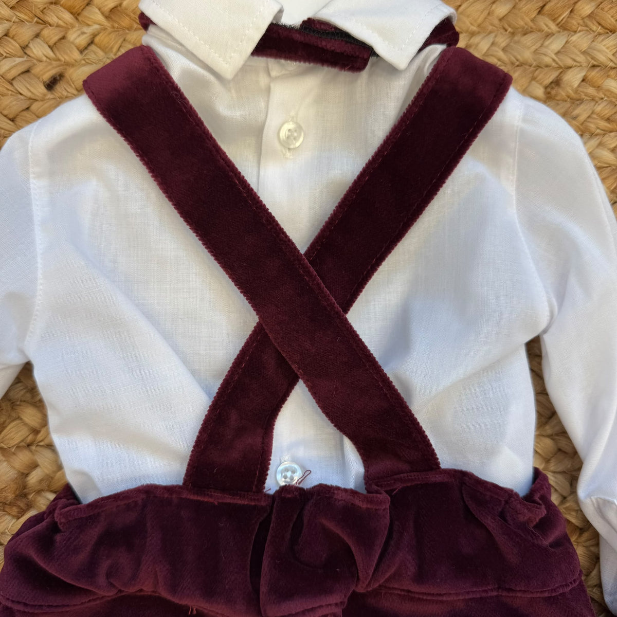 Retro completo battesimo bimbo con bretelle incrociate e fiocco in velluto bordeaux su camicia bianca.