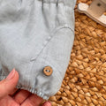 Dettaglio bottoncino in legno su pantaloncino lino celeste