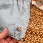 Dettaglio bottoncino in legno su pantaloncino lino celeste