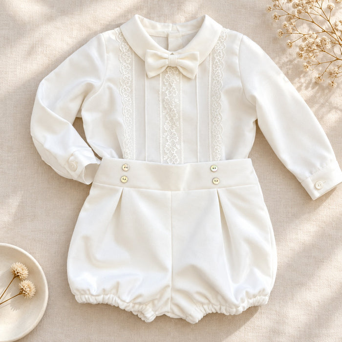 Completo battesimo neonato bianco con camicia a maniche lunghe decorata in pizzo floreale, papillon e pantaloncino a palloncino.