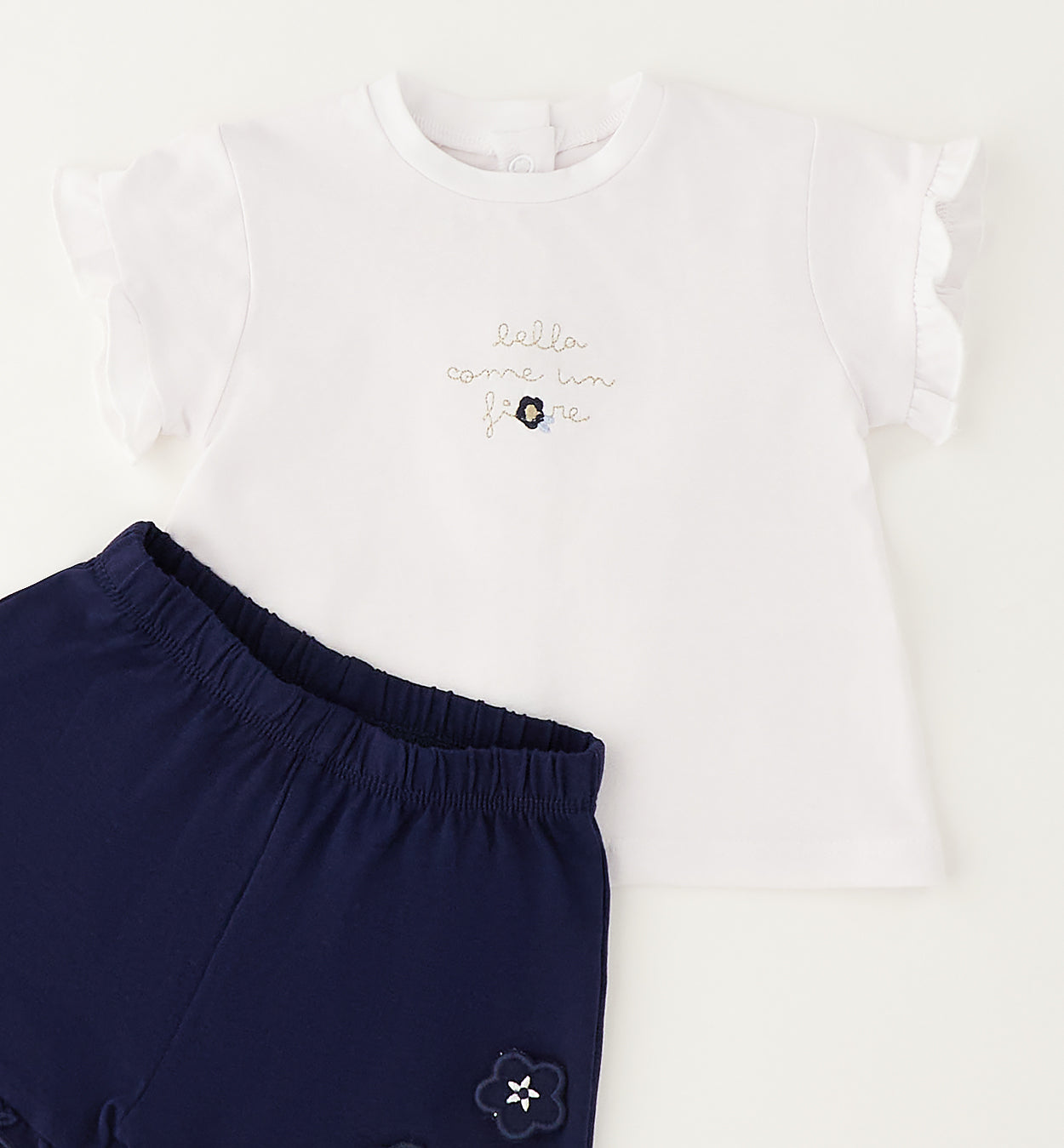 Dettaglio completo bimba con maglia bianca a volant e shorts blu elasticizzati