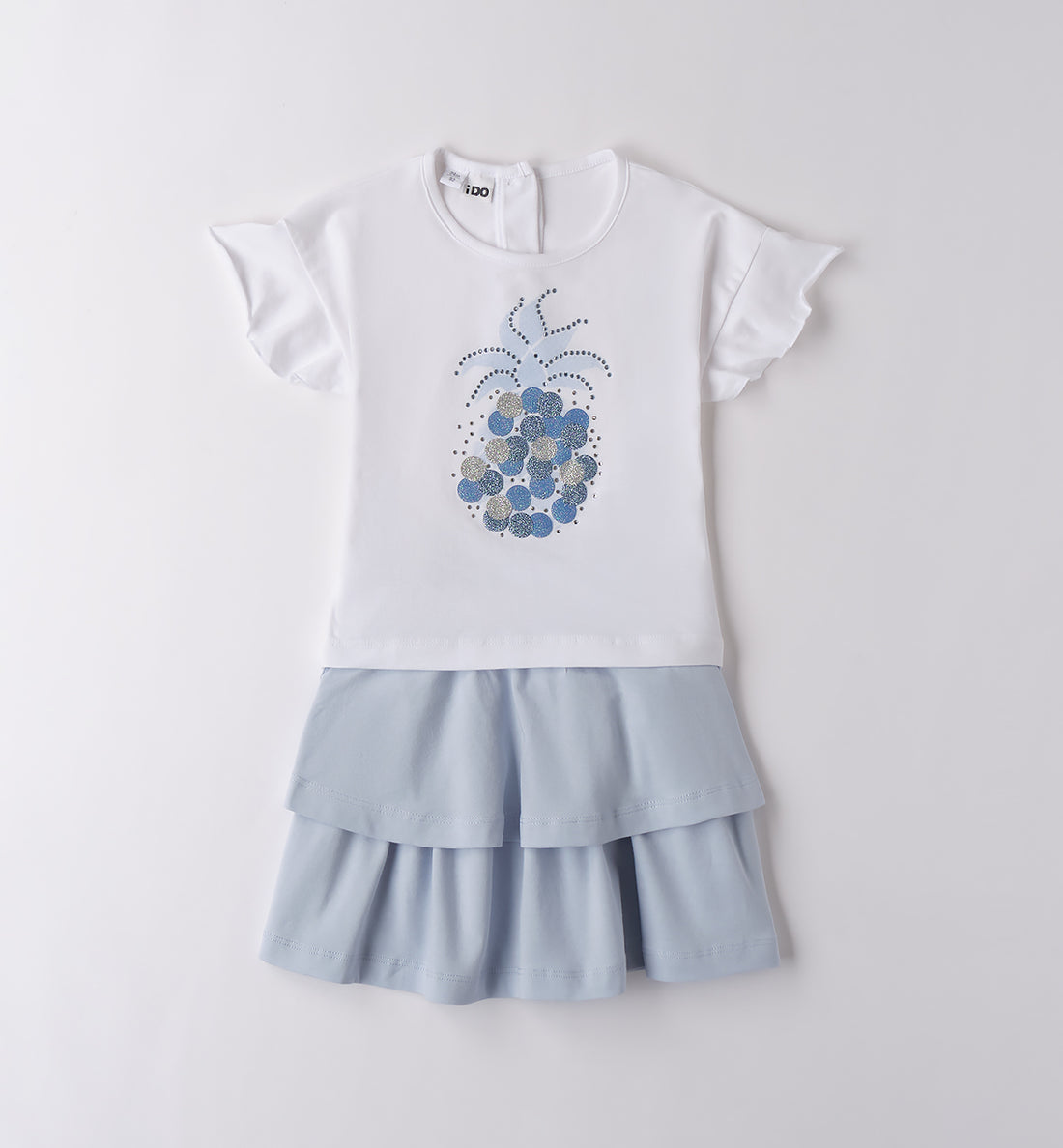 Completo bambina con t-shirt bianca ananas glitter e gonna azzurra a balze.