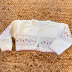 Salopette in lana panna con orsetta e colletto rosa, abbinata a gilet cuori per neonata.