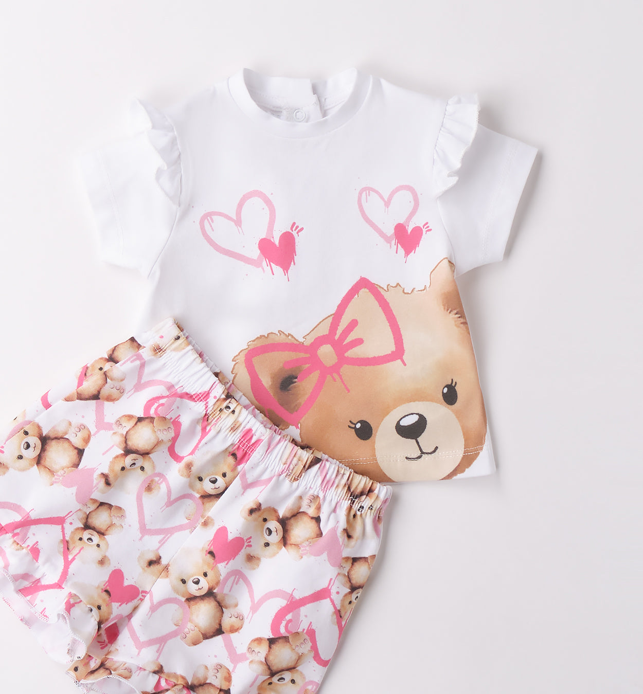 Dettaglio completo bambina piegato con t-shirt orsetto e pantaloncini fantasia cuori.