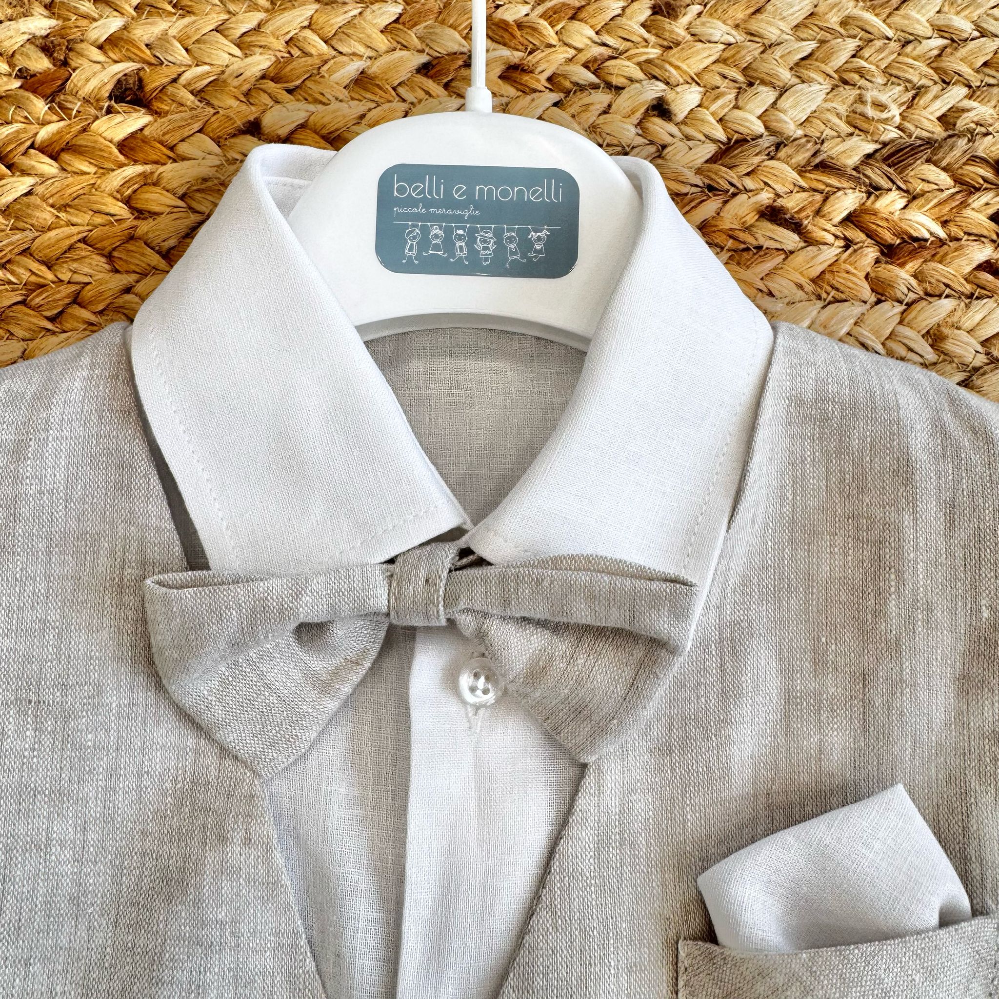 Dettaglio della camicia bianca e del papillon in lino beige coordinato.
