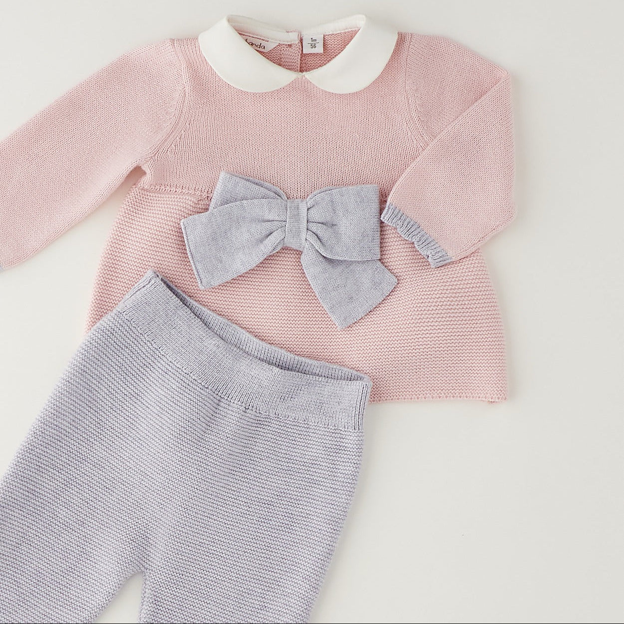 Completo neonata rosa e grigio in cotone e lana con fiocco, pantalone e cappellino coordinato.