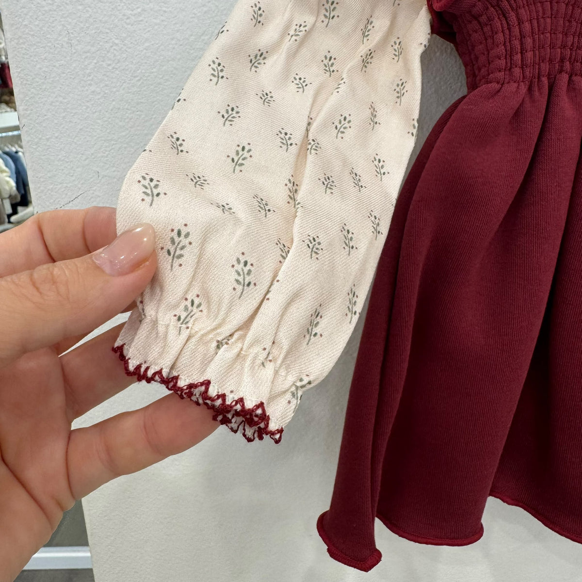 Dettaglio del colletto arricciato della camicetta panna con fantasia floreale e bordino bordeaux.