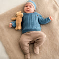 
Completo neonato in cotone e lana con maglia petrolio a trecce e pantalone beige indossato