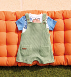 Completo neonato con salopette verde in maglina e t-shirt con maniche blu e stampa astratta.