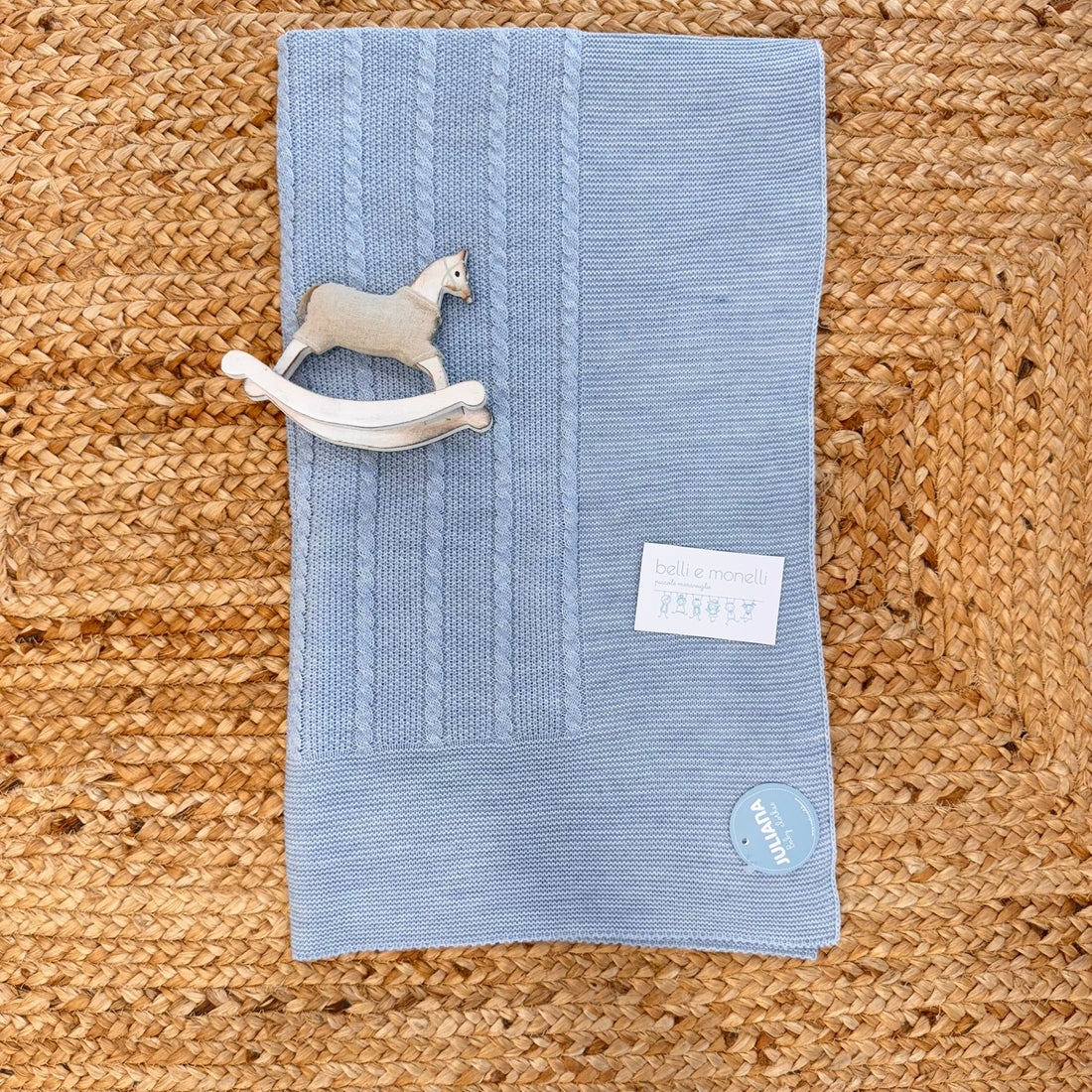 Copertina neonato in maglia azzurra con trecce e cavalluccio decorativo


