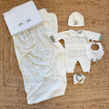 Uscita clinica neonata panna con tutina, copertina, lenzuola e accessori coordinati.