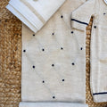 Tutina neonato beige in lana e cotone con dettagli blu e bavetta bianca con orsetto ricamato